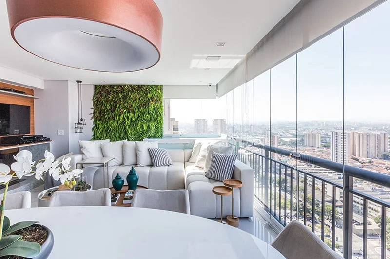 Projeto Eucaglass: sacada envidraçada integrada à sala de estar com vista da cidade